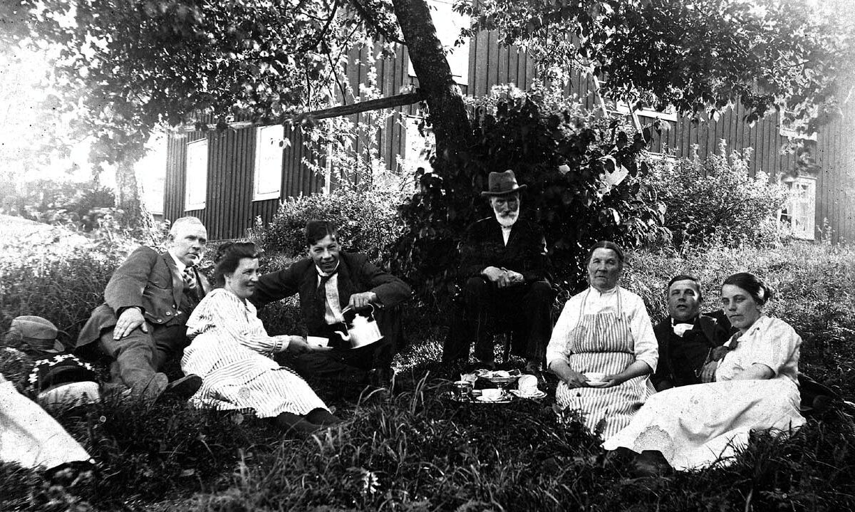 En grupp människor har picknick i gräset utanför Arbetarmuseet Gråbo.