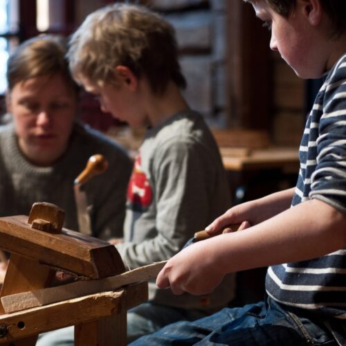 Två pojkar sitter på varsin täljhäst i en loge.